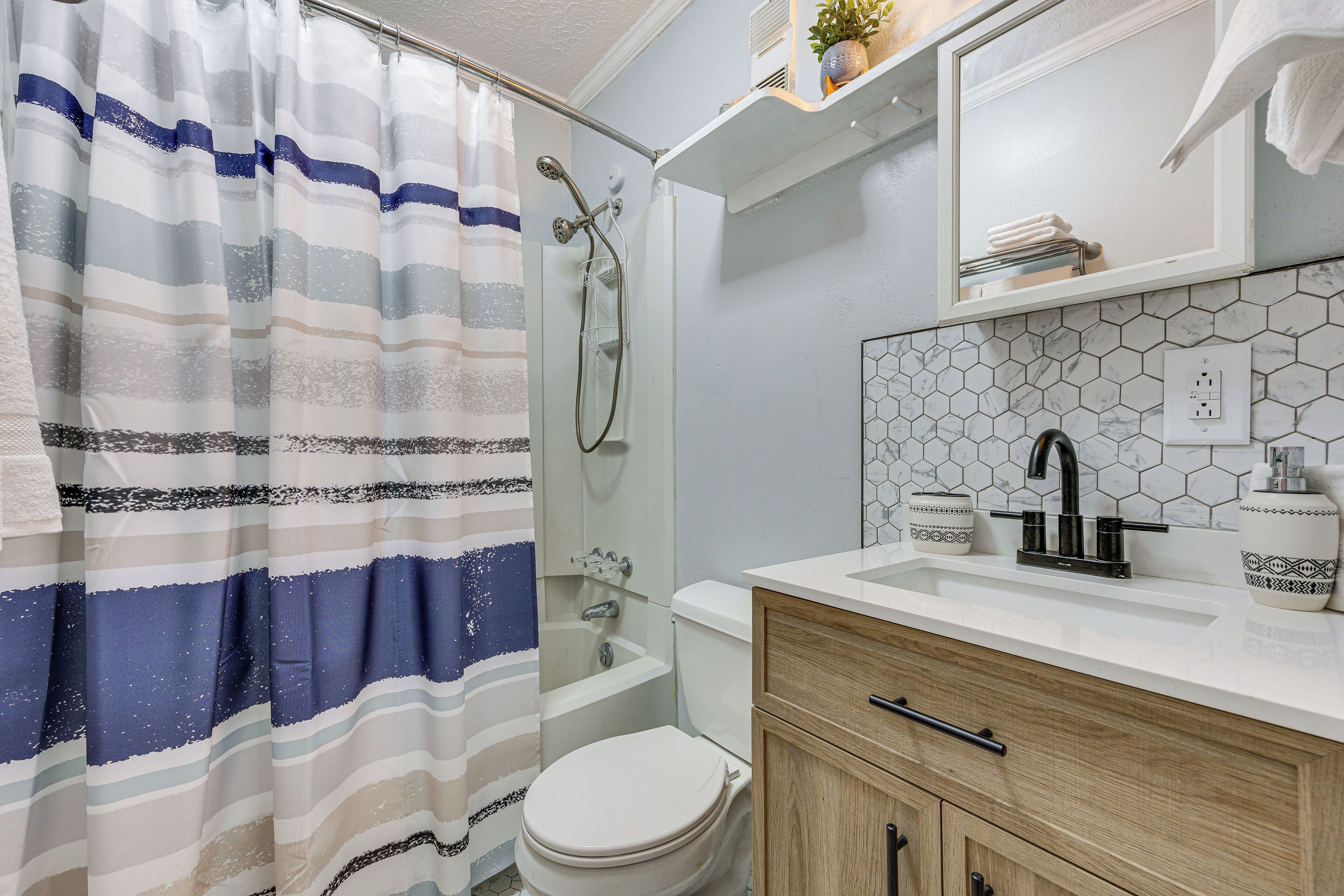 A bathroom with a shower, toilet, and a sink with a mirror above it.