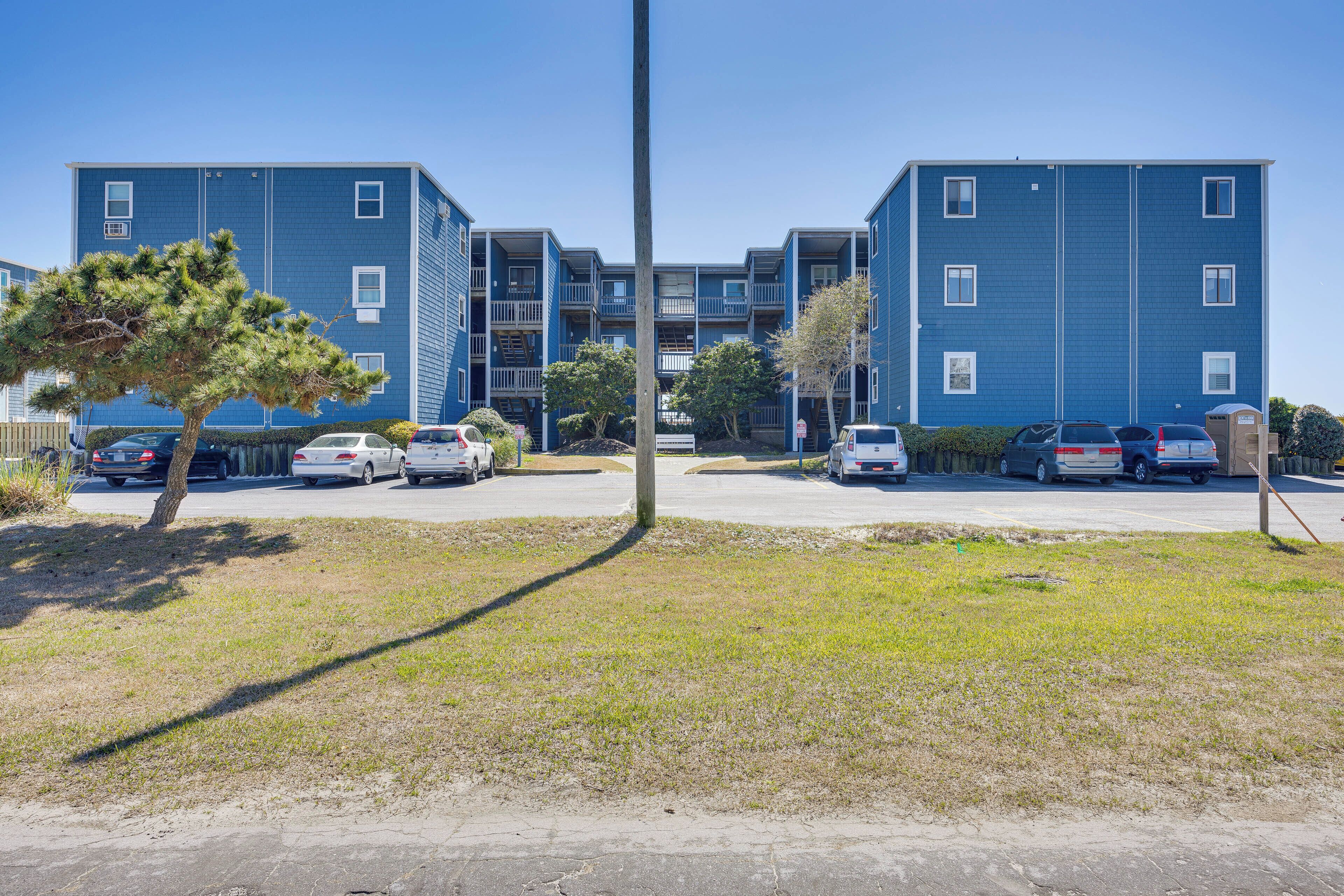 A multi-story residential building with a parking lot in front.