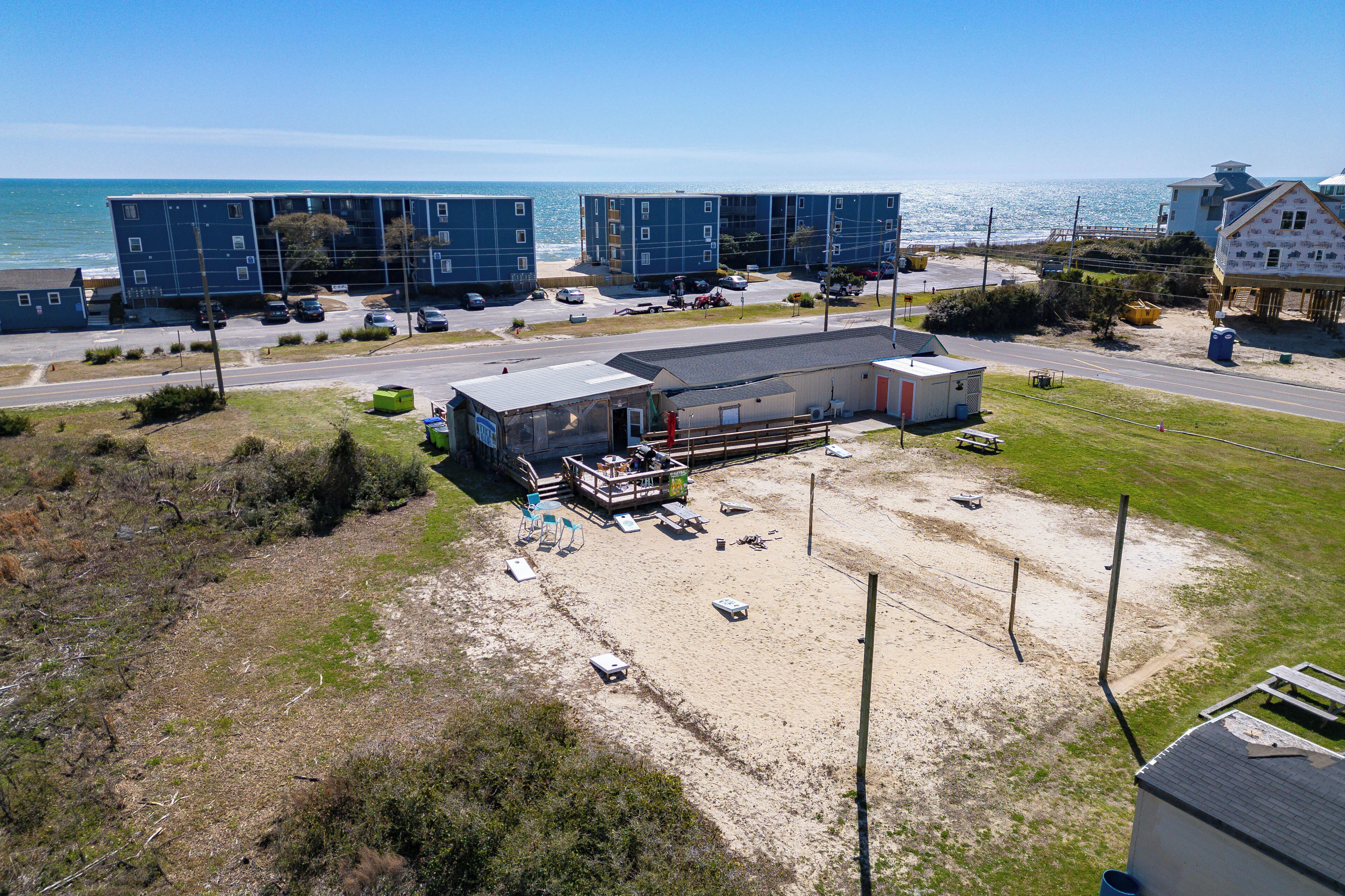 Een complex aan de kust met meerdere appartementen, een parkeerplaats en een zandstrand.