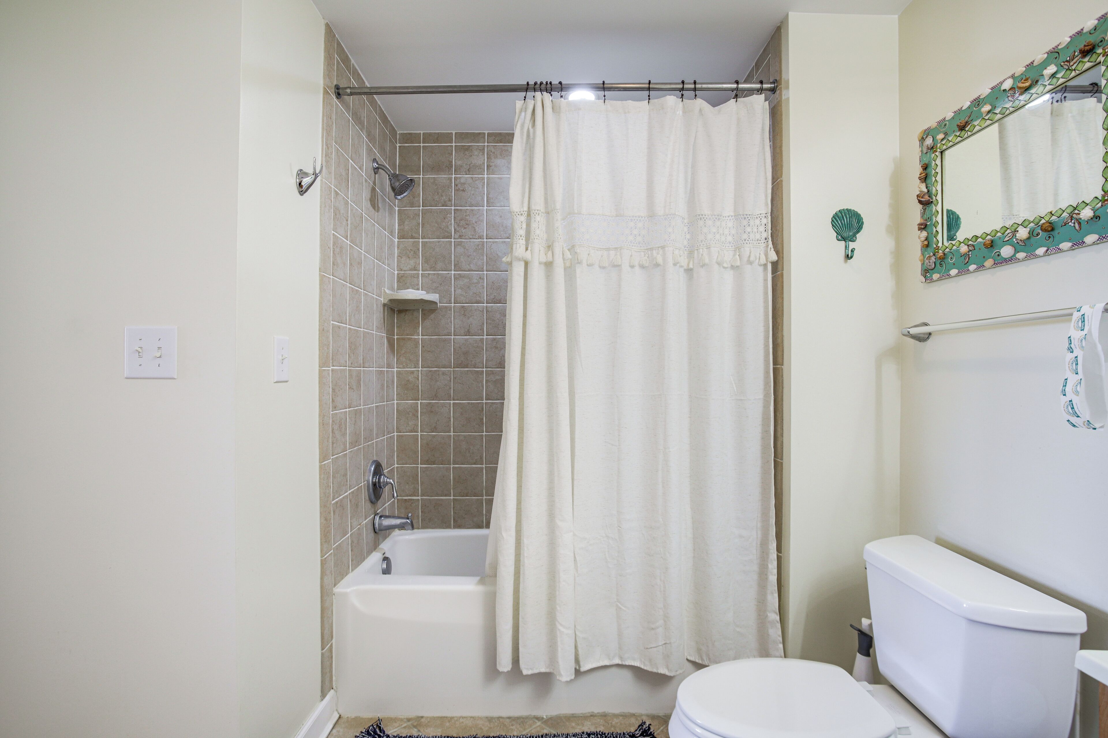 A bathroom with a bathtub, toilet, and a shower curtain.