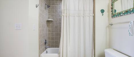 A bathroom with a bathtub, toilet, and a shower curtain.
