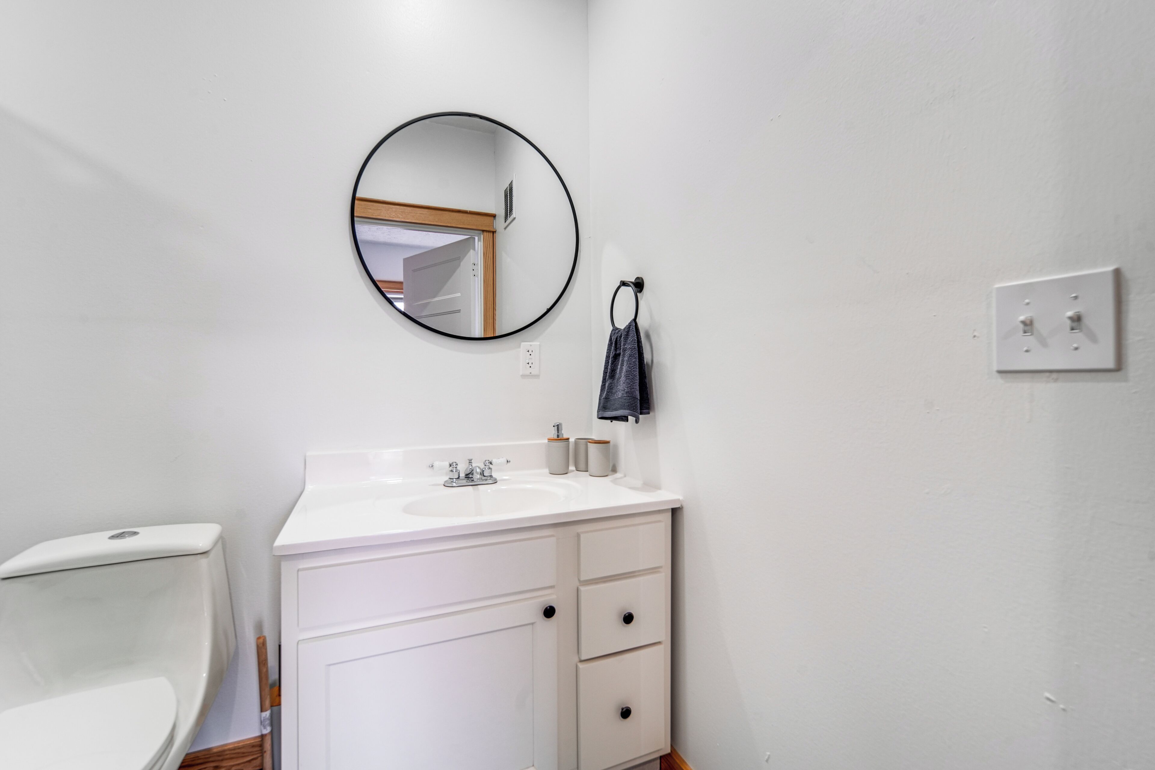 Une salle de bain avec un lavabo blanc, un miroir et des toilettes.