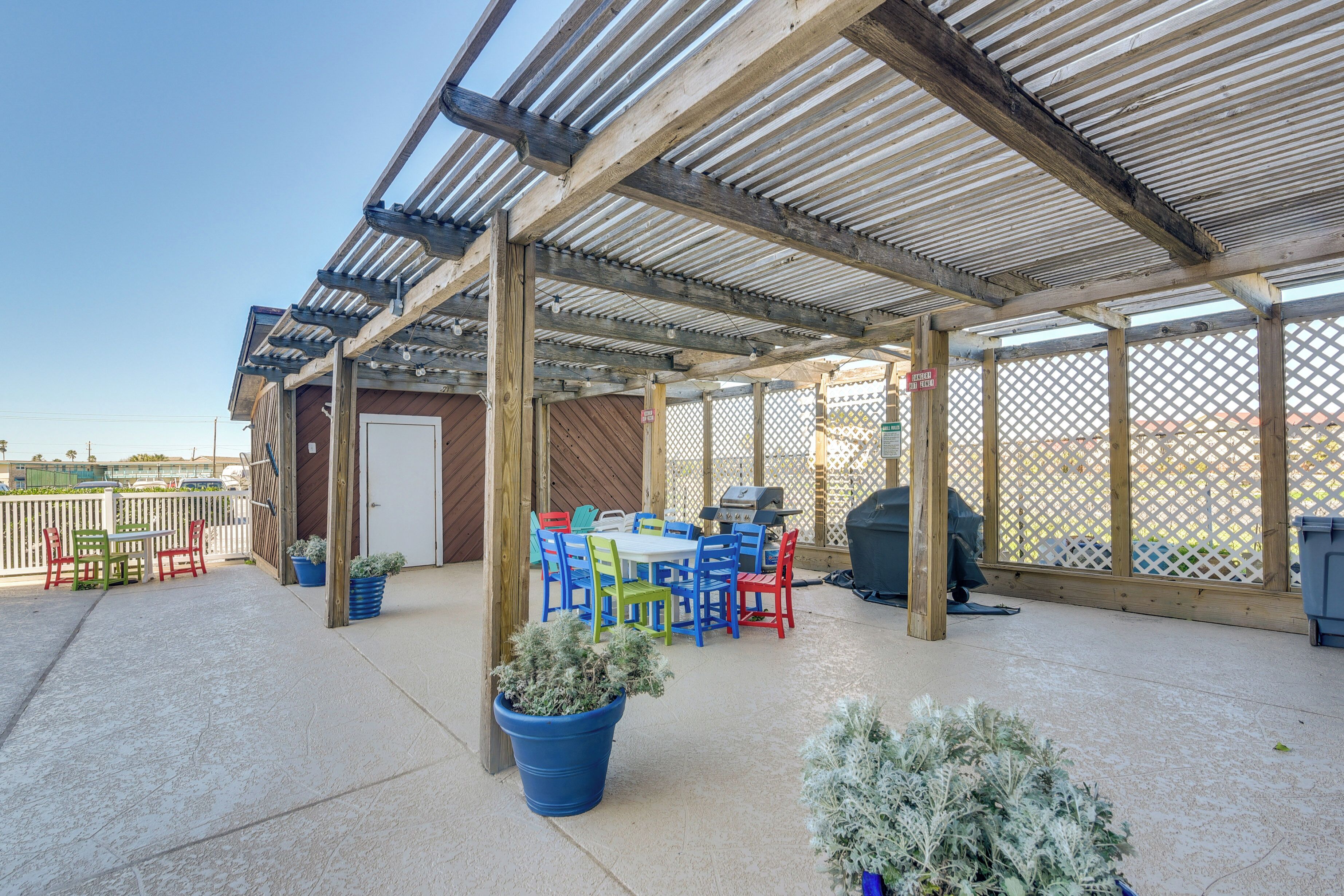 An outdoor patio area with a covered seating area, a grill, and potted plants.