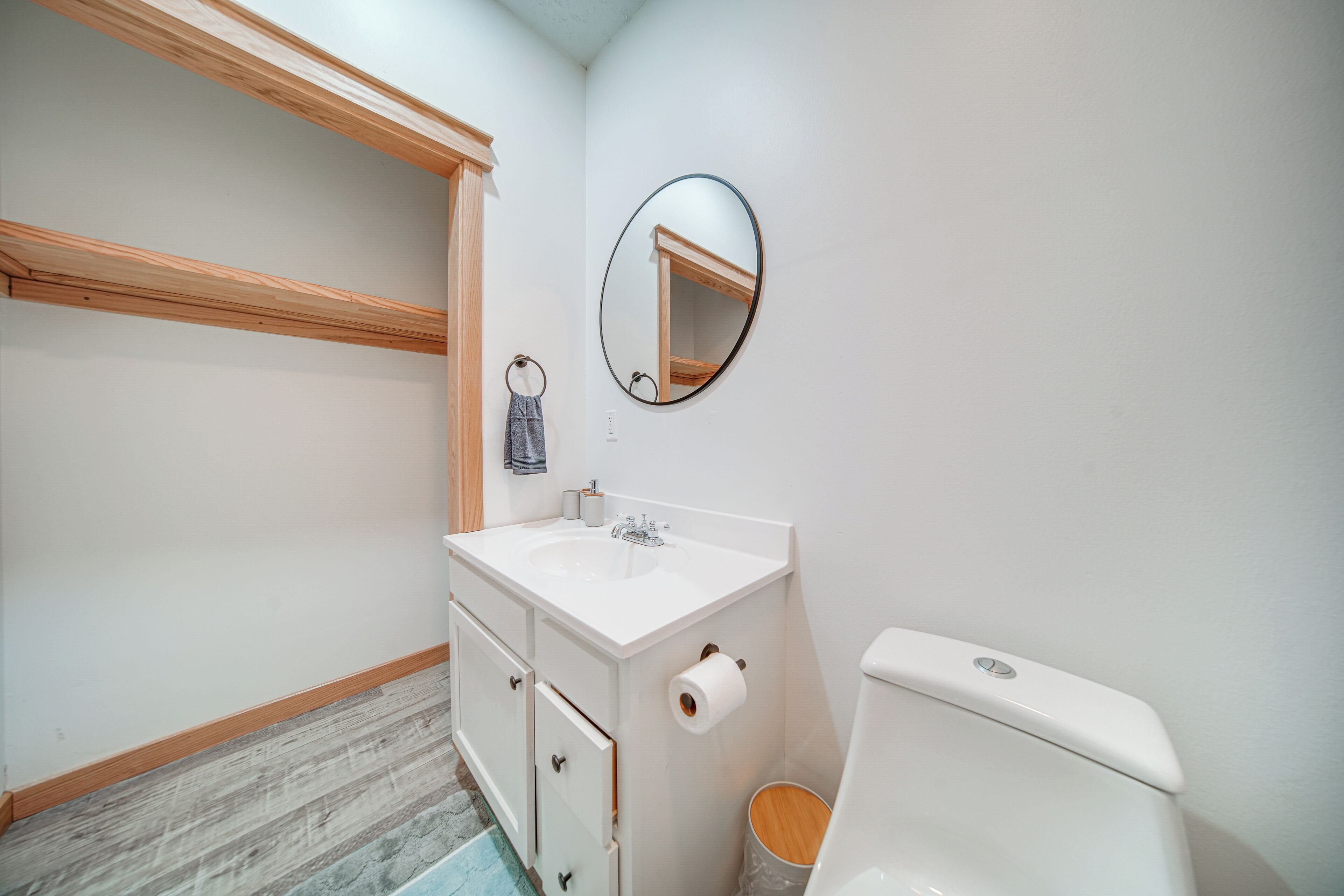 Une salle de bain avec un lavabo blanc, un meuble-lavabo en bois, un miroir et des toilettes.