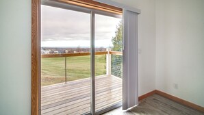 Una stanza con un'ampia porta finestra scorrevole che si apre su un balcone con pavimento in legno.