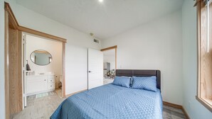 Una camera da letto con un letto grande, una cassettiera, uno specchio e una porta che dà su un'altra stanza.