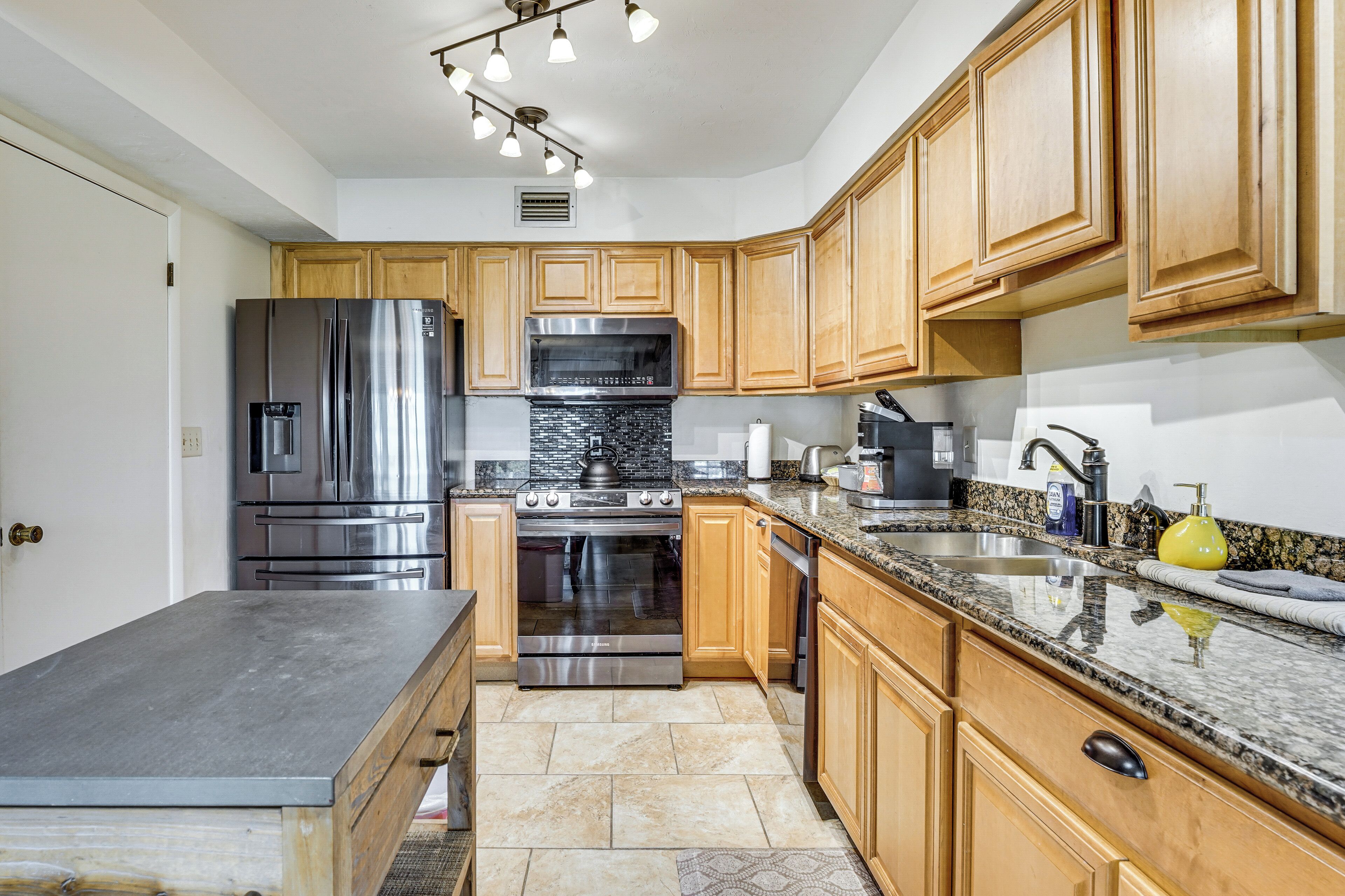 A kitchen with wooden cabinets, stainless steel appliances, granite countertops, and a built-in oven.