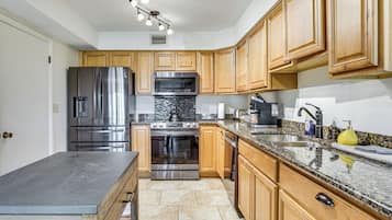 A kitchen with wooden cabinets, stainless steel appliances, granite countertops, and a built-in oven.