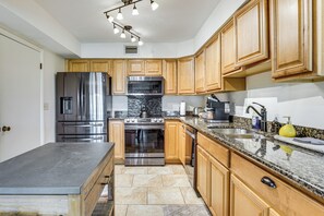 Cozinha com armários de madeira, eletrodomésticos de aço inoxidável, bancadas de granito e forno embutido.