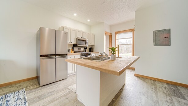 A modern kitchen with stainless steel appliances, a wooden countertop, and a large island. - 4 Mi to Lake Erie: Condo w/ Golf Course Views! (Erie)