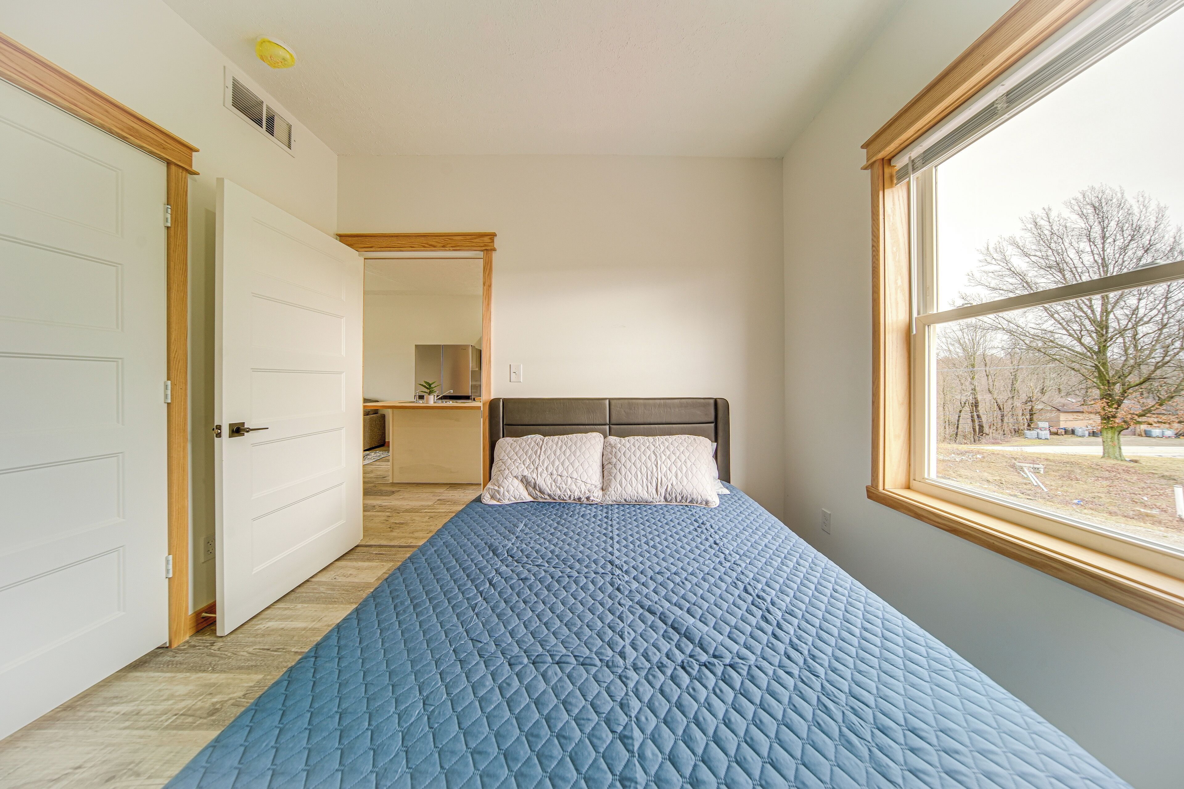 A bedroom with a bed, a window, and a door.