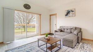 A living room with a sofa, a coffee table, a clock, and a painting. - 4 Mi to Lake Erie: Condo w/ Golf Course Views! (Erie)