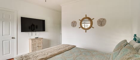 Een slaapkamer met een bed, een televisie, een plafondventilator en wanddecoraties.