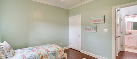 A bedroom with two beds, a ceiling fan, and a door leading to a bathroom.