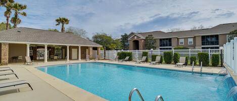 A swimming pool with lounge chairs and a covered seating area.