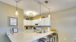 A modern kitchen with a large island, bar stools, and pendant lighting. - Panama City Beach Home: Steps to the Ocean! (Panama City Beach)