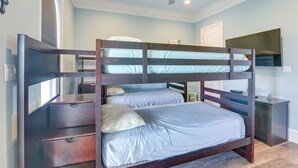 A bunk bed with two levels, a ceiling fan, a bedside table, and a TV on the wall.