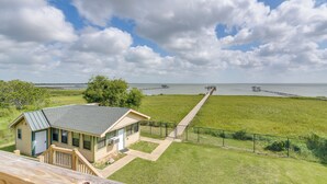 A house with a deck overlooking a grassy area and a body of water.