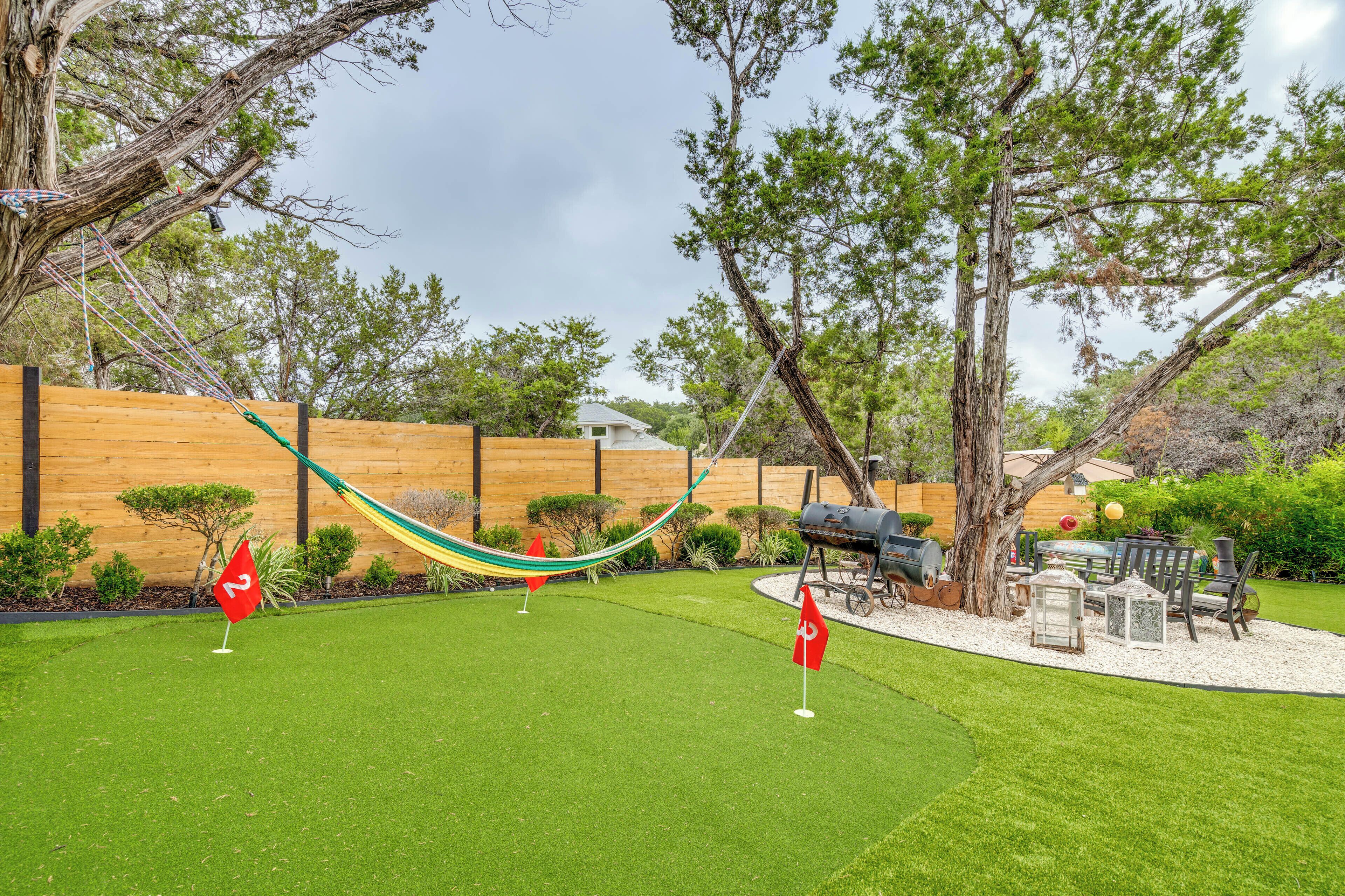 A backyard with a hammock, a barbecue area, and a flag.