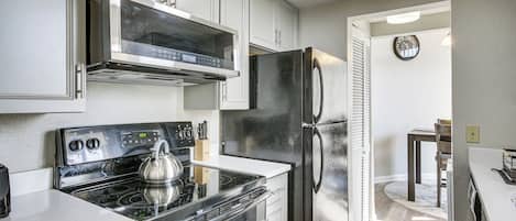 A modern kitchen with stainless steel appliances, white cabinetry, and a built-in microwave.