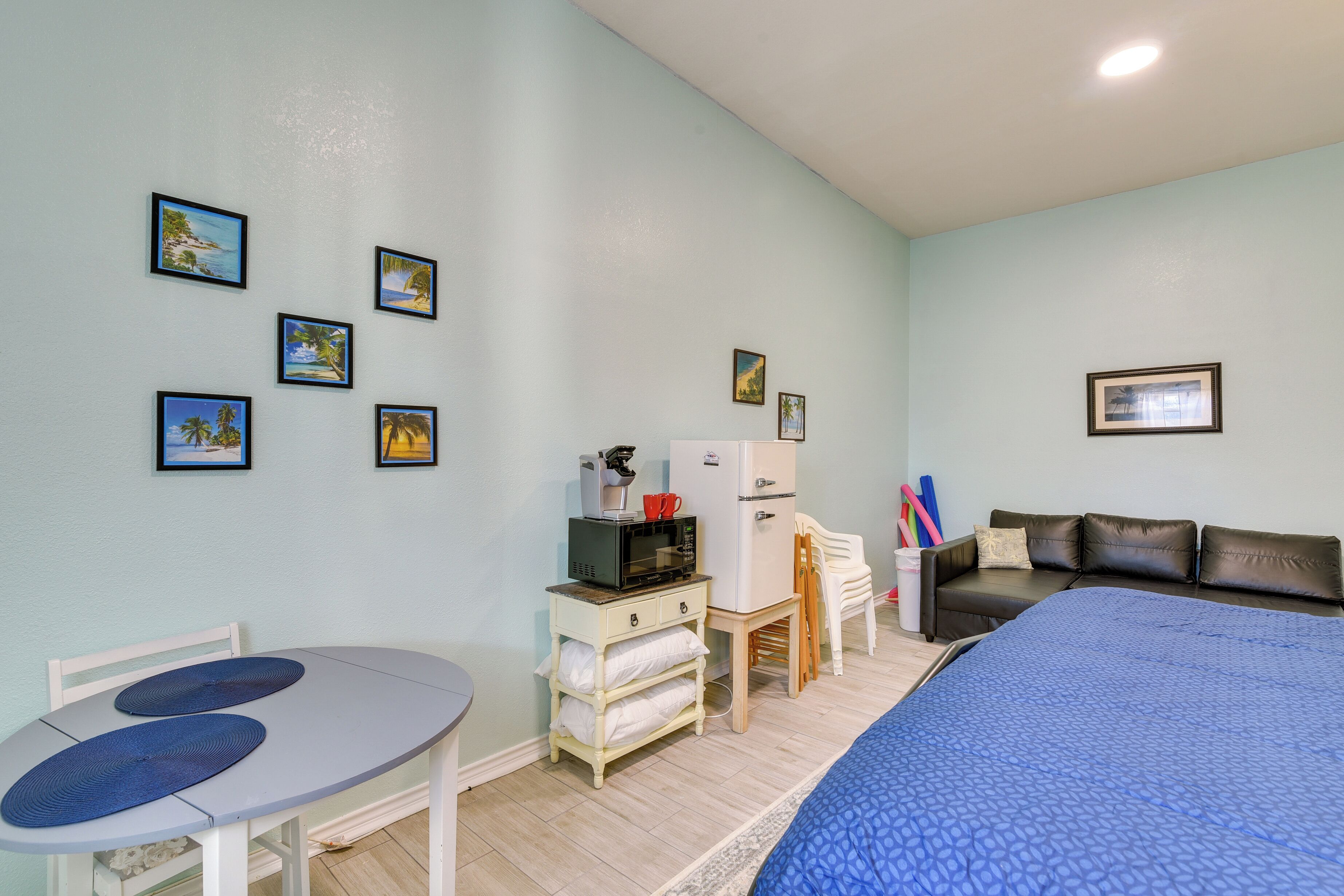 A room with a bed, a table, a refrigerator, and a couch.