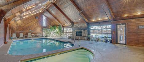 An indoor swimming pool with wooden beams and a stone wall.
