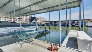 A covered dock area with a boat, a table with chairs, and a water pump. - Lakefront Condo w/ Resort Amenities in Osage Beach (Osage Beach)