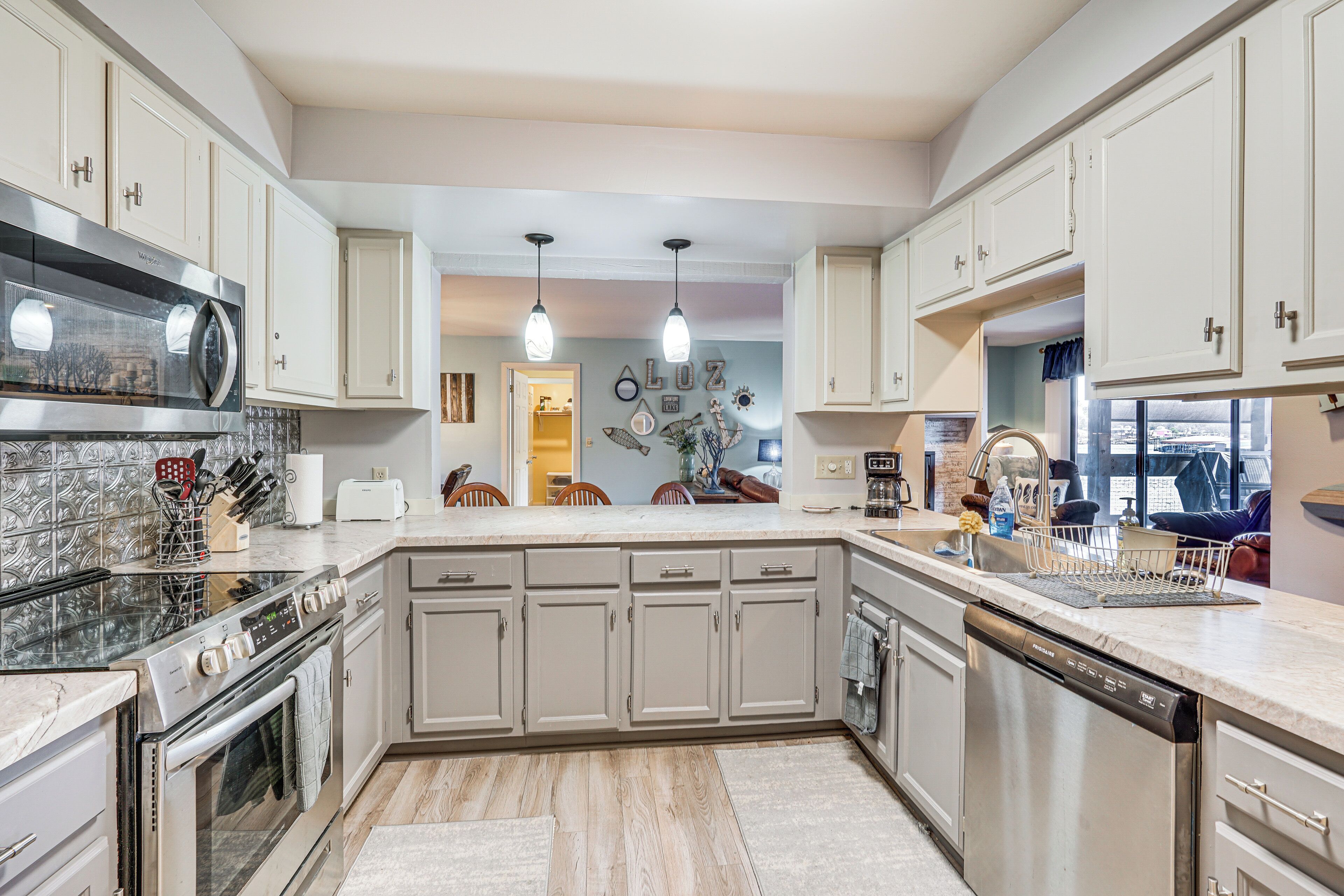 A modern kitchen with a built-in oven, microwave, and dishwasher, featuring light-colored cabinetry and a marble countertop.