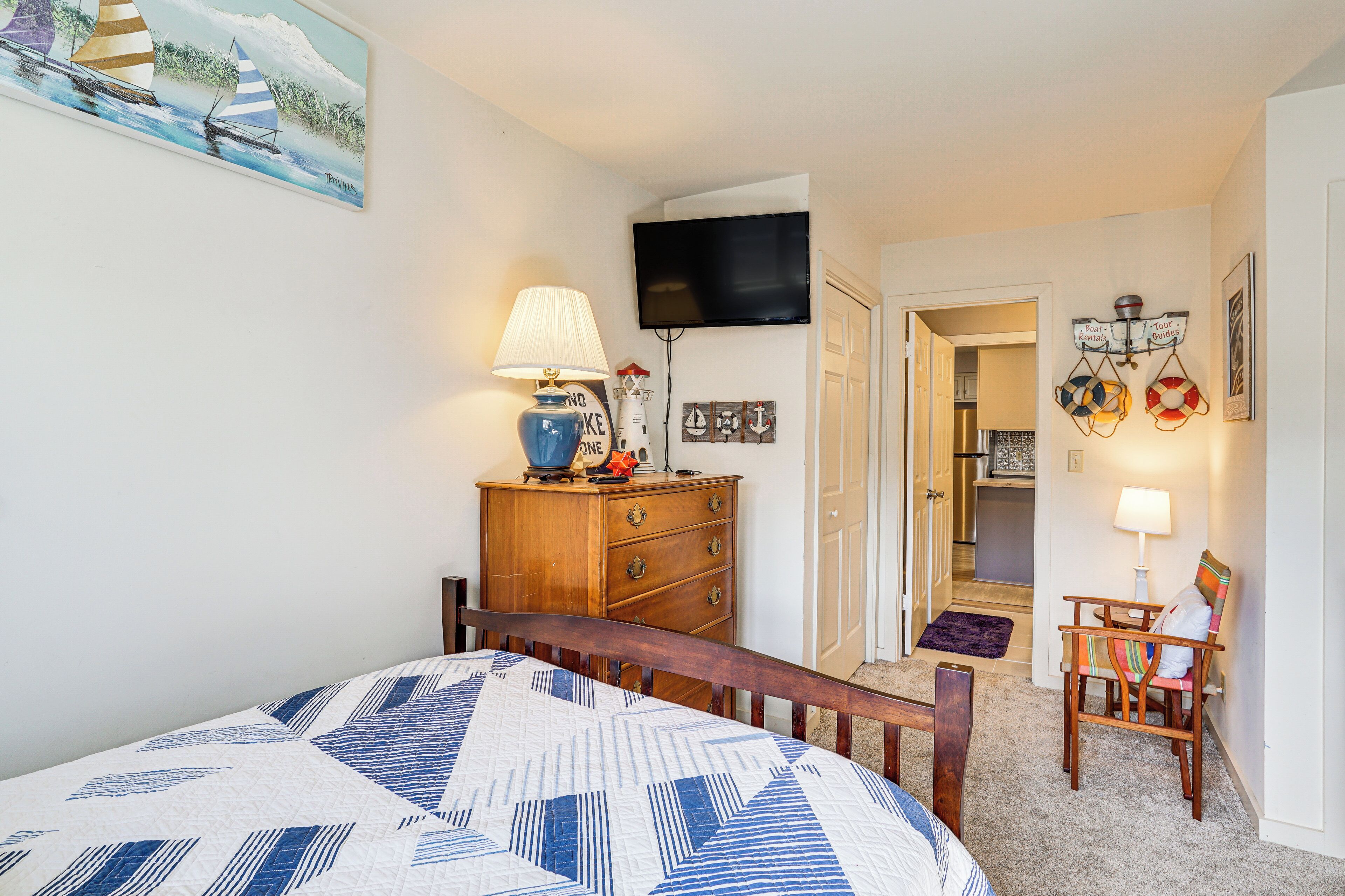 A bedroom with a bed, a dresser, a television, and a chair.