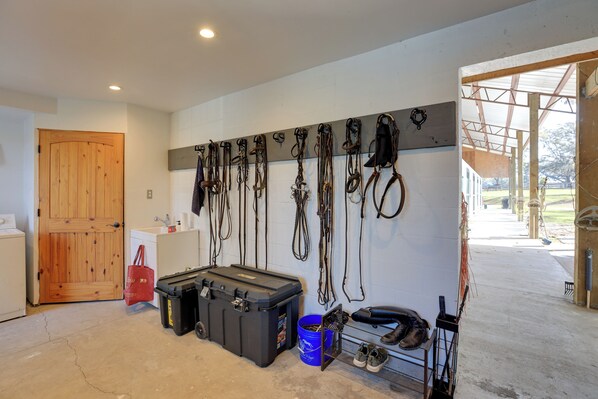 A garage with a wooden door, a sink, a toolbox, and a wall-mounted rack holding various tools and equipment.