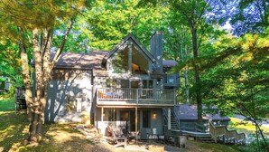 A cabin with a balcony, outdoor seating, and a fireplace. - Calm in the Woods Fireplace Walk to Town (Suttons Bay)