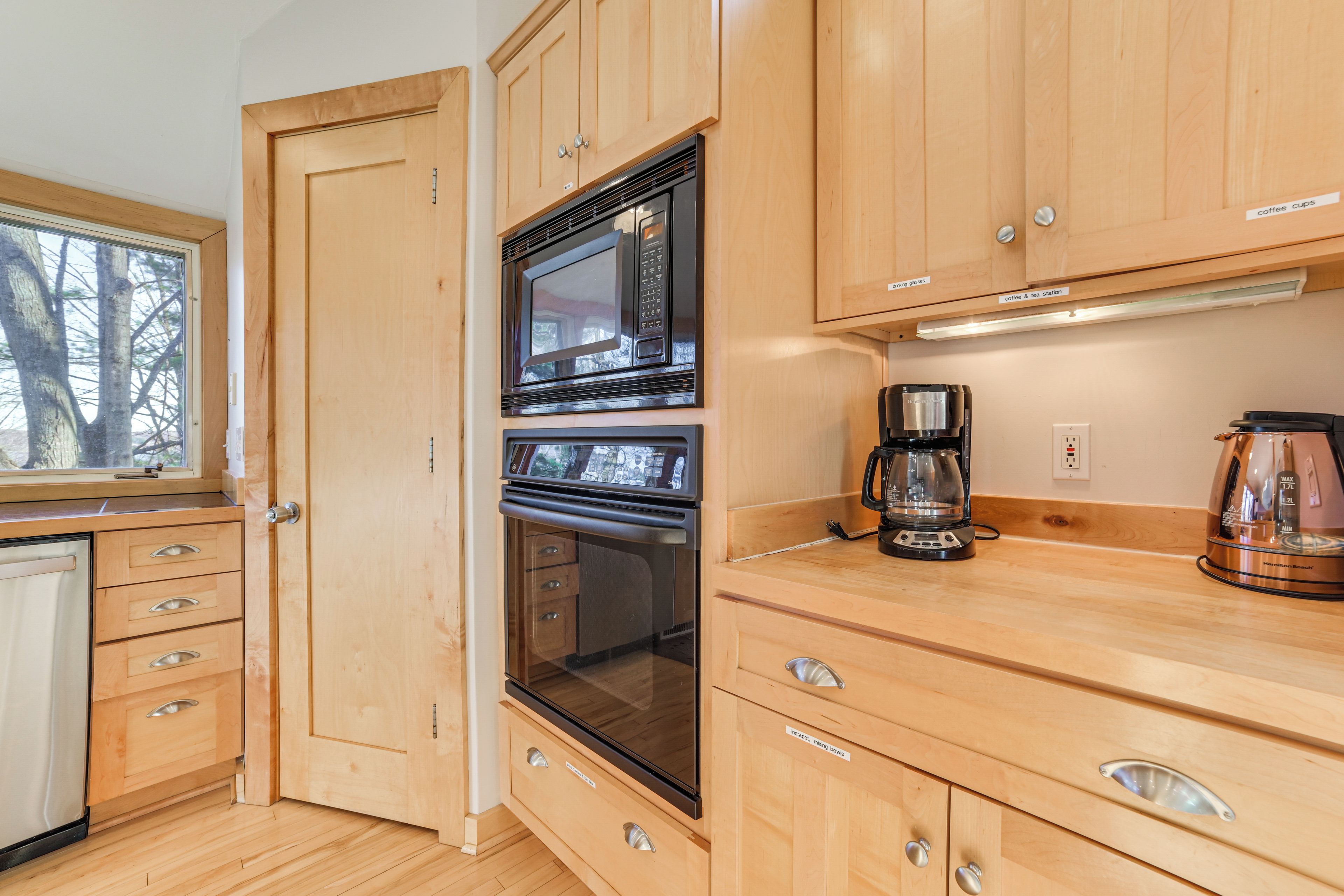 A kitchen with wooden cabinets, a microwave, an oven, and a coffee maker.