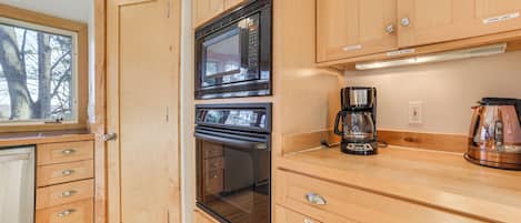 A kitchen with wooden cabinets, a microwave, an oven, and a coffee maker.