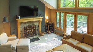 A living room with a fireplace, a sofa, a coffee table, and a television. - Calm in the Woods Fireplace Walk to Town (Suttons Bay)