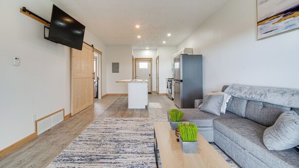 A modern living room with a grey sofa, a coffee table, and a flat-screen TV mounted on the wall. - 4 Mi to Lake: Golf-view Erie Condo w/ Porch (Erie)