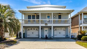 A two-story building with a white facade, a balcony on the upper floor, and a garage with two doors.
