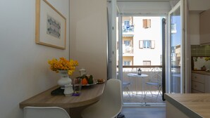 A dining area with a wooden table, white chairs, a vase of yellow flowers, and a framed picture on the wall. - Le Boulevard (Corfu)