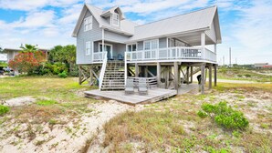 A beachfront house with a balcony, a staircase, and a sandy surrounding. - Pet Friendly | Gulf Views | Golf Cart | Deeded Beach Access (Gulf Shores)