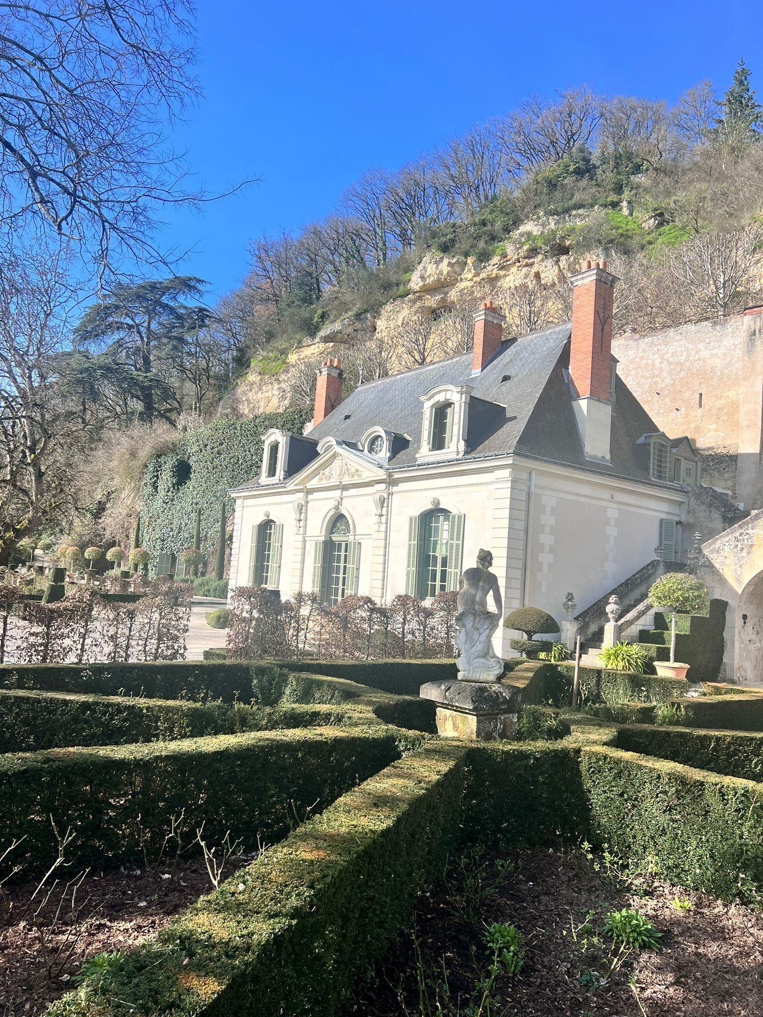 Un bâtiment imposant, doté d’une façade symétrique, d’une entrée centrale et d’une statue en premier plan.