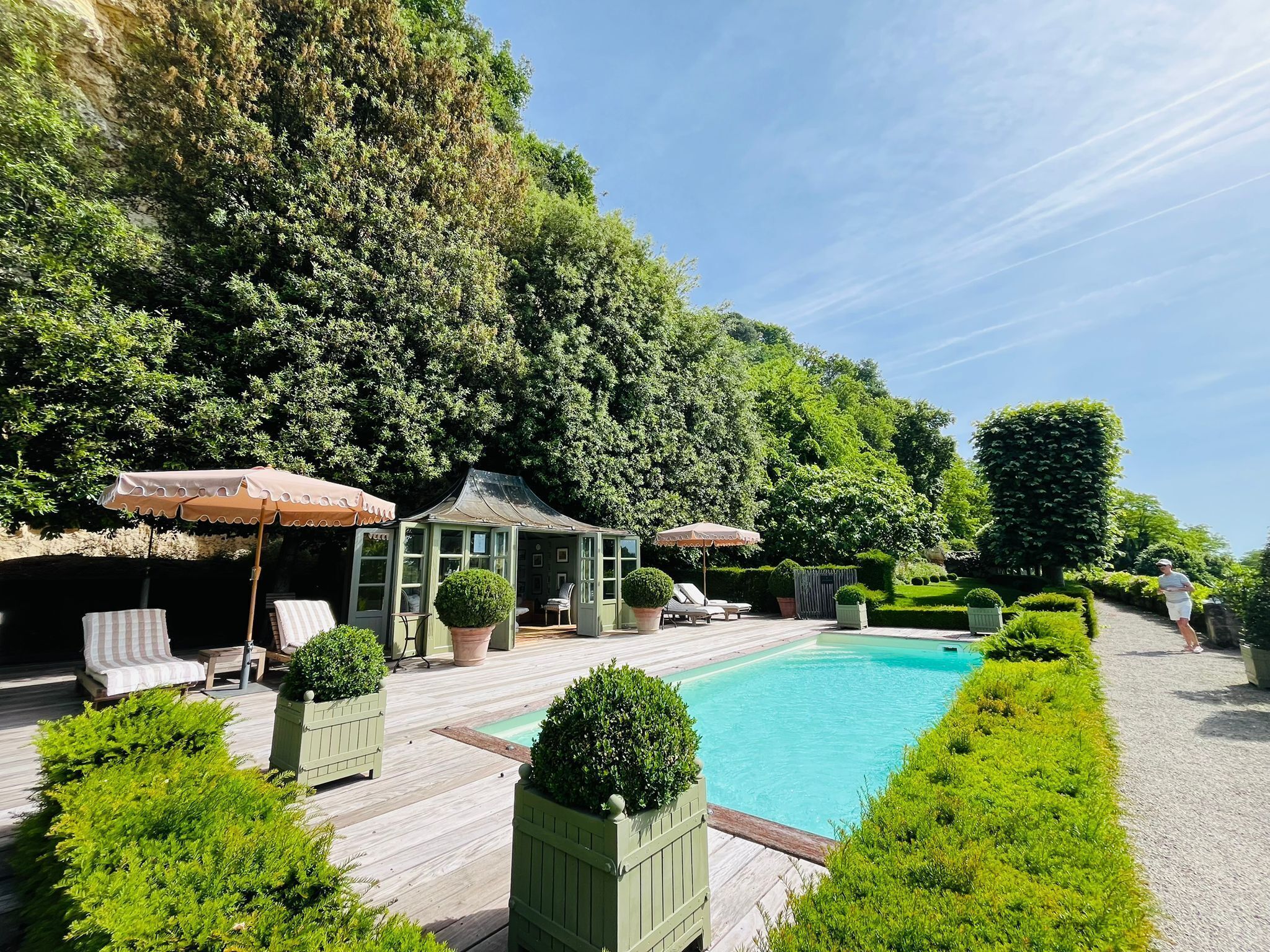 Ein Poolbereich mit Liegestühlen, einem Wintergarten und einem gepflegten Garten.