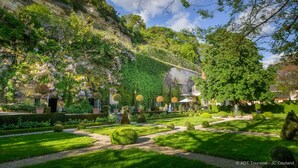 A garden with a pathway, neatly trimmed hedges, and a building with a stone facade. - MANOIR DES BASSES RIVIERES (Rochecorbon)
