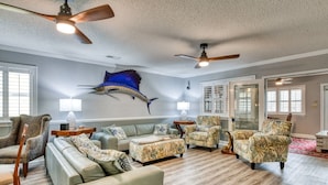 A spacious living room with a large wall mural, multiple ceiling fans, and a variety of seating options. - Five Bedroom, Four and Half Bath, Channel front, and Private Pool (Murrells Inlet)