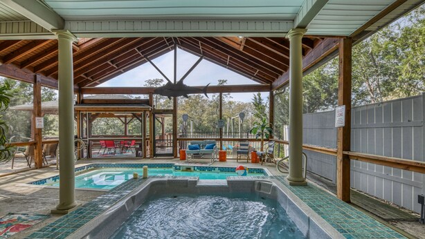 A covered outdoor swimming pool with a hot tub, lounge chairs, and a quiet zone sign. - Five Bedroom, Four and Half Bath, Channel front, and Private Pool (Murrells Inlet)