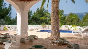 A dining area with a pool view, white lounge chairs, and a tropical setting. - CostaBlancaDreams - Villa Palmeraie in Calpe (Calpe)