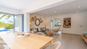 A spacious living area with a wooden dining table, wicker chairs, a sofa with cushions, and a large mirror on the wall. - CostaBlancaDreams - Villa Palmeraie in Calpe (Calpe)