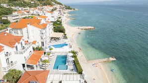 A coastal hotel with a swimming pool, beach access, and hillside views.