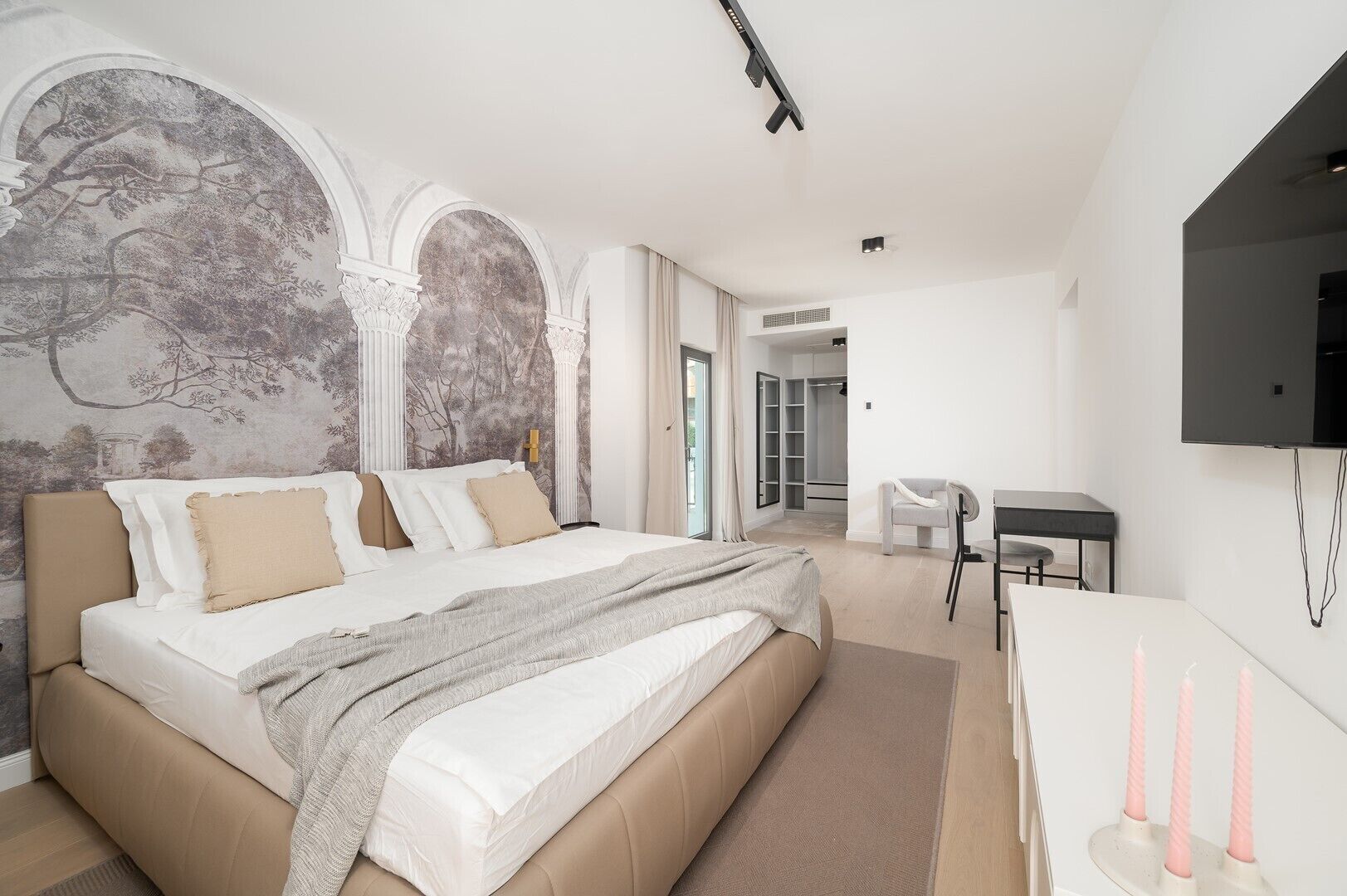 Een moderne slaapkamer met een groot bed, een bureau en een televisie.
