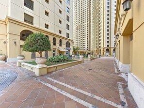 Stroll through this tranquil courtyard, surrounded by lush greenery and a majestic tree.
