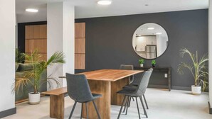 A modern dining area with a wooden table and chairs, a large mirror on the wall, and potted plants. - Glorious !  1BR King! Free Parking !30 min to NYC (orange)
