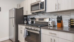 A modern kitchen with stainless steel appliances, wooden cabinets, and a marble backsplash. - Glorious !  1BR King! Free Parking !30 min to NYC (orange)